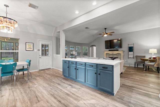 kitchen featuring pendant lighting, ceiling fan with notable chandelier, blue cabinetry, lofted ceiling, and light wood-type flooring