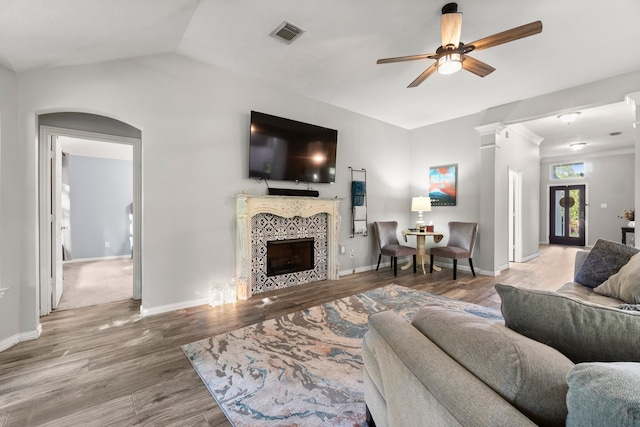 living room featuring lofted ceiling, wood-type flooring, a tile fireplace, and ceiling fan