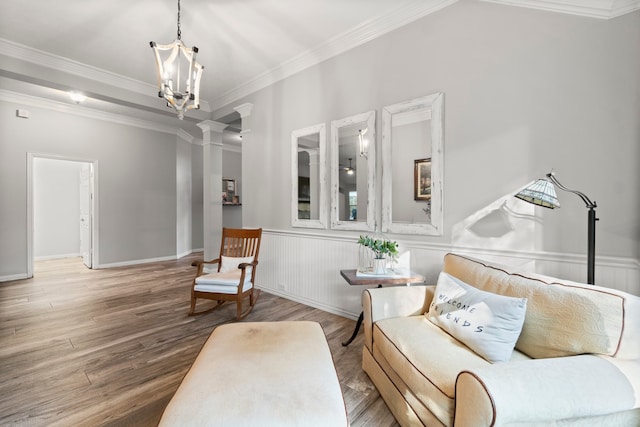 sitting room with hardwood / wood-style flooring, ornate columns, crown molding, and a notable chandelier