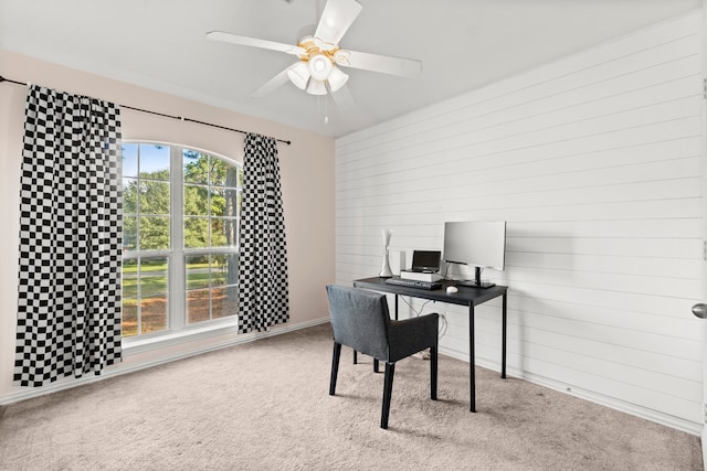 office area with wood walls, carpet floors, and ceiling fan