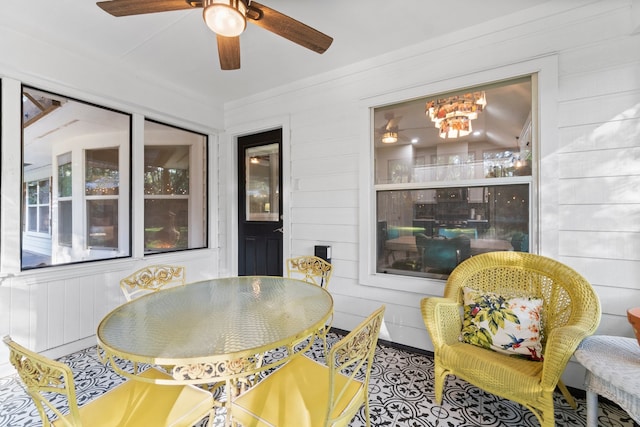 dining area with ceiling fan and wooden walls