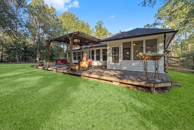 rear view of property featuring a lawn, a sunroom, a wooden deck, and a pergola