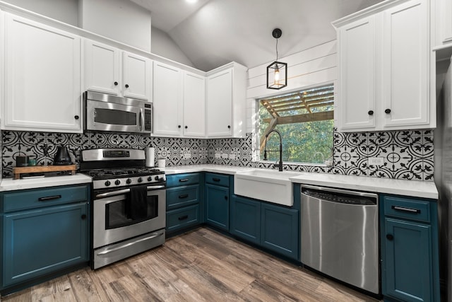 kitchen featuring sink, appliances with stainless steel finishes, tasteful backsplash, blue cabinetry, and pendant lighting