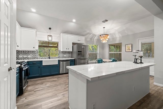 kitchen featuring white cabinetry, appliances with stainless steel finishes, decorative light fixtures, hardwood / wood-style floors, and blue cabinets