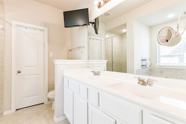 bathroom with a shower with door, vanity, toilet, and tile patterned floors