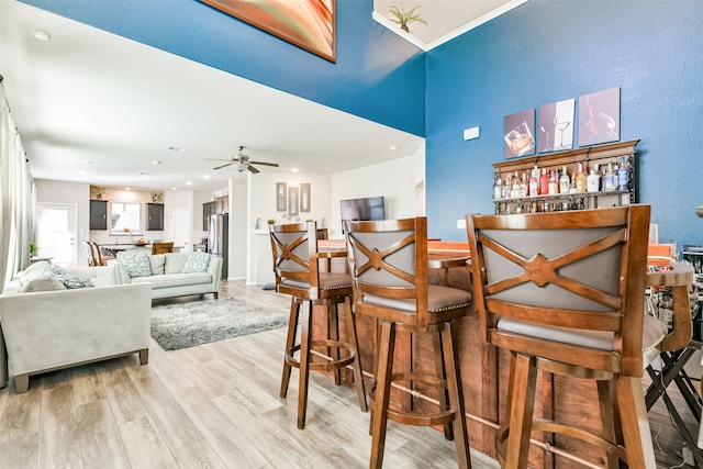 bar with light hardwood / wood-style floors and ceiling fan