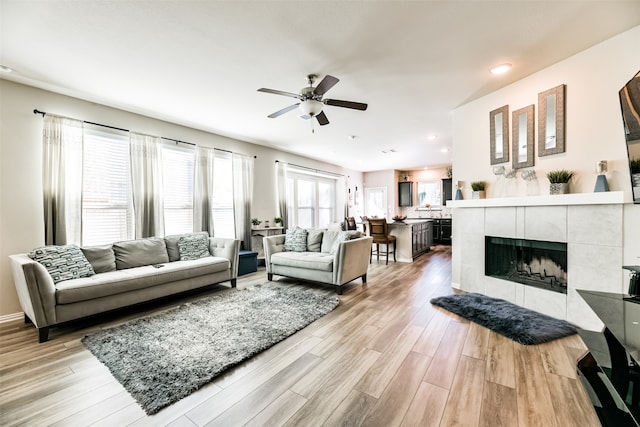 living room featuring light hardwood / wood-style floors, a fireplace, and ceiling fan