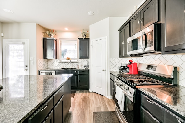 kitchen featuring light hardwood / wood-style floors, stainless steel appliances, stone counters, and plenty of natural light