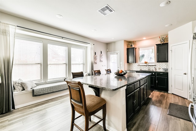 kitchen featuring a kitchen breakfast bar, dark stone countertops, a center island, and plenty of natural light