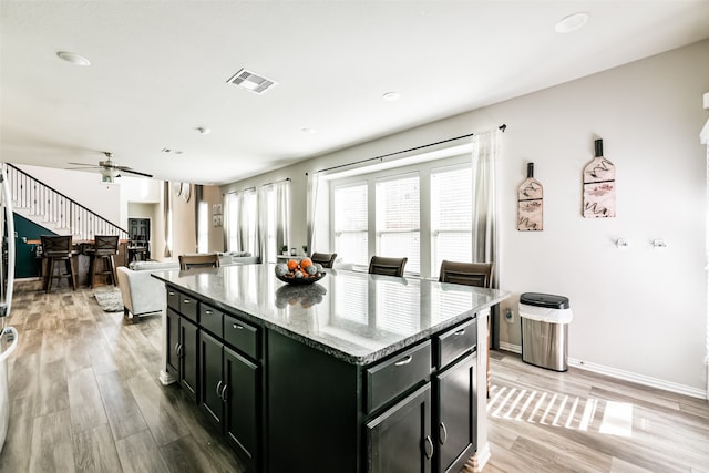 kitchen featuring a kitchen island, light stone countertops, light hardwood / wood-style flooring, and ceiling fan