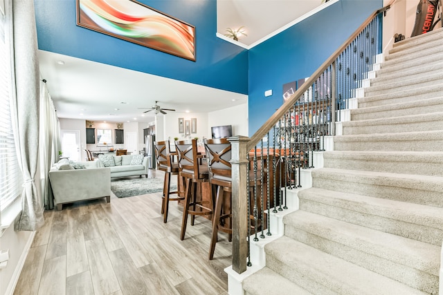 stairway with hardwood / wood-style flooring, a towering ceiling, and ceiling fan