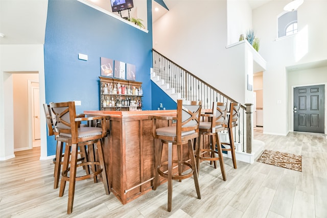 bar with a high ceiling and light hardwood / wood-style floors