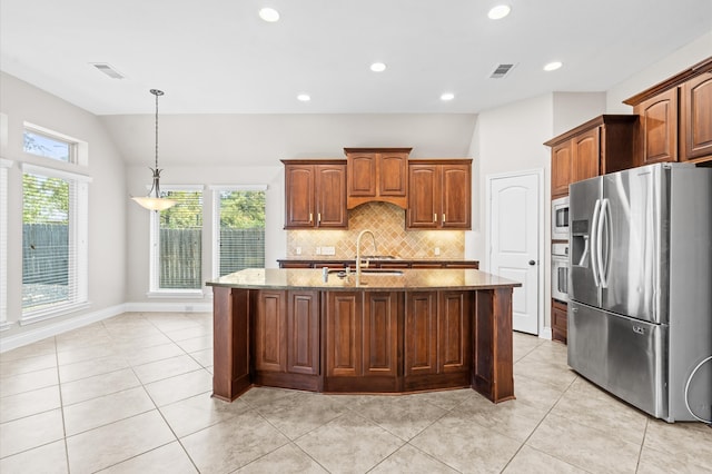 kitchen featuring lofted ceiling, a kitchen island with sink, stainless steel appliances, sink, and light stone countertops