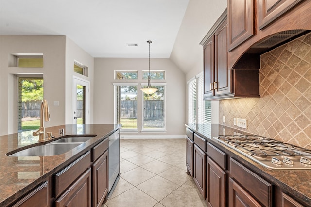 kitchen featuring backsplash, dark stone counters, sink, light tile patterned flooring, and appliances with stainless steel finishes