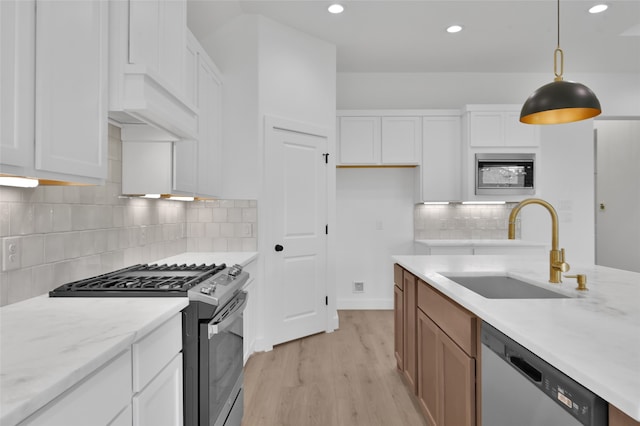 kitchen with appliances with stainless steel finishes, sink, decorative light fixtures, and white cabinets