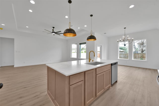 kitchen featuring sink, a kitchen island with sink, hanging light fixtures, and a healthy amount of sunlight