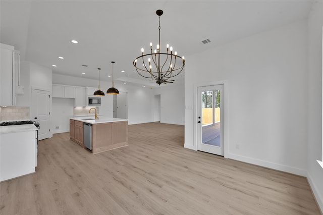 kitchen featuring hanging light fixtures, a center island with sink, white cabinets, appliances with stainless steel finishes, and light hardwood / wood-style floors