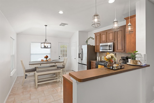 kitchen with appliances with stainless steel finishes, backsplash, lofted ceiling, decorative light fixtures, and a chandelier