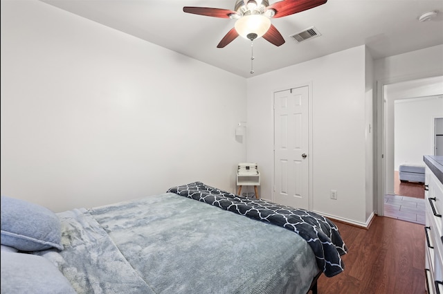 bedroom with dark wood-type flooring, heating unit, and ceiling fan