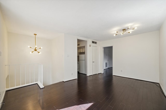 empty room featuring an inviting chandelier and dark hardwood / wood-style flooring