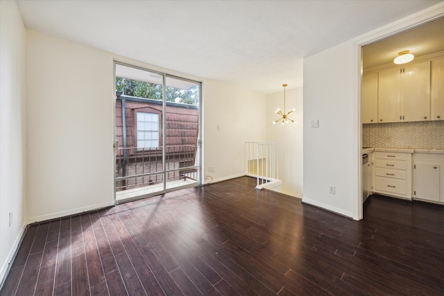 empty room featuring dark wood-type flooring and an inviting chandelier