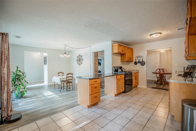 kitchen featuring a textured ceiling, decorative light fixtures, black range with gas cooktop, a notable chandelier, and light hardwood / wood-style flooring