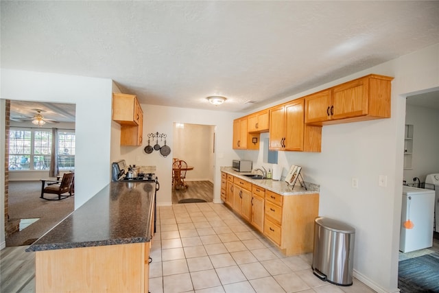 kitchen featuring ceiling fan, a textured ceiling, light tile patterned flooring, washing machine and dryer, and sink