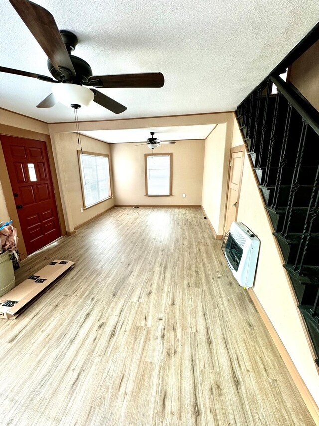 106 E Main St E, Wortham, TX 76693 - unfurnished living room featuring heating unit, light wood finished floors, a ceiling fan, stairway, and a textured ceiling