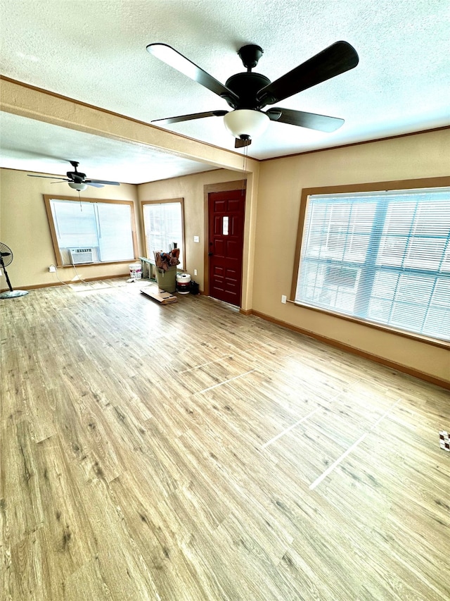 unfurnished living room featuring ceiling fan, a healthy amount of sunlight, a textured ceiling, and light hardwood / wood-style flooring