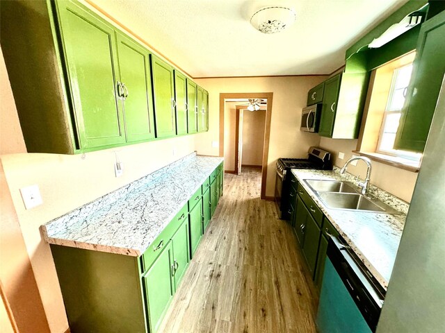 106 E Main St E, Wortham, TX 76693 - kitchen with green cabinetry, appliances with stainless steel finishes, a sink, light wood-style flooring, and light countertops