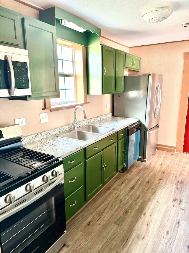 kitchen with light hardwood / wood-style floors, appliances with stainless steel finishes, sink, and green cabinetry