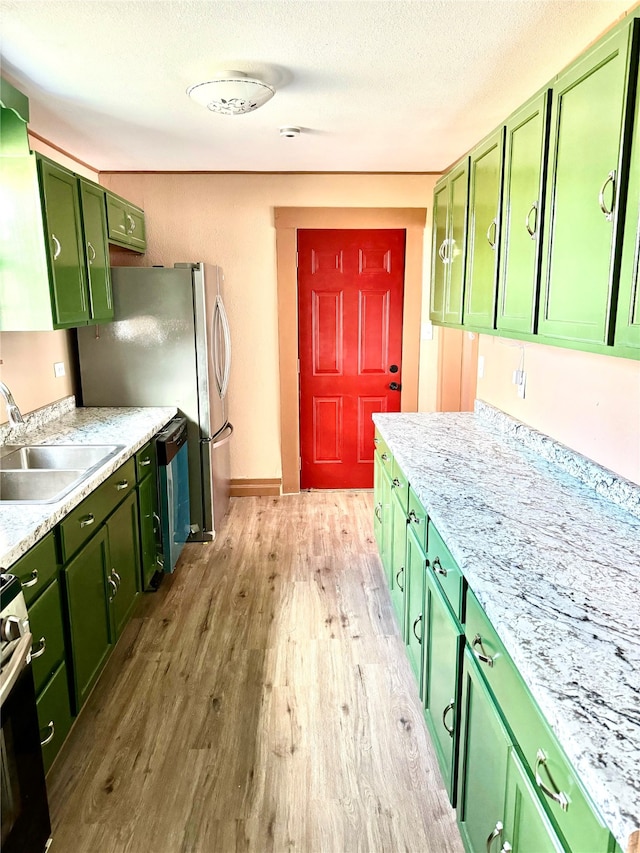 kitchen featuring sink, electric range oven, a textured ceiling, green cabinets, and light hardwood / wood-style flooring