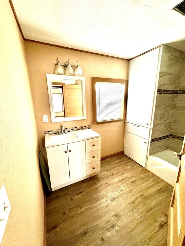 106 E Main St E, Wortham, TX 76693 - full bath featuring wood finished floors, a bath, vanity, baseboards, and a shower