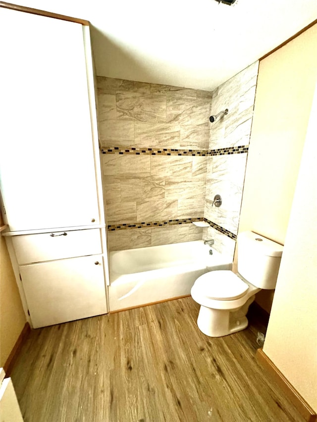 bathroom with tiled shower / bath, hardwood / wood-style flooring, and toilet