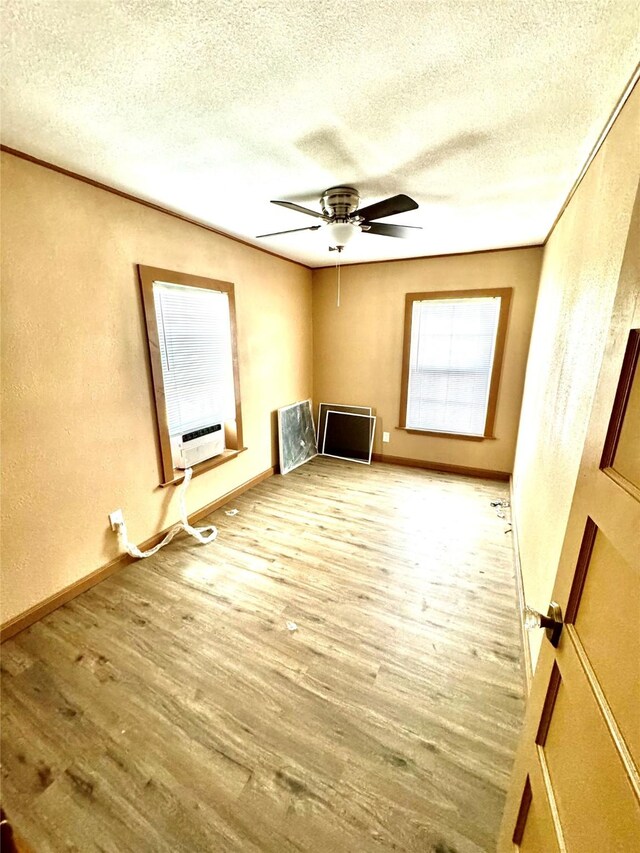 106 E Main St E, Wortham, TX 76693 - empty room with a textured ceiling, wood finished floors, ceiling fan, a textured wall, and baseboards