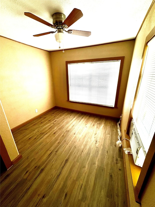 spare room featuring ceiling fan, wood-type flooring, and a wealth of natural light