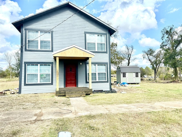 view of front of property featuring a storage shed and a front lawn