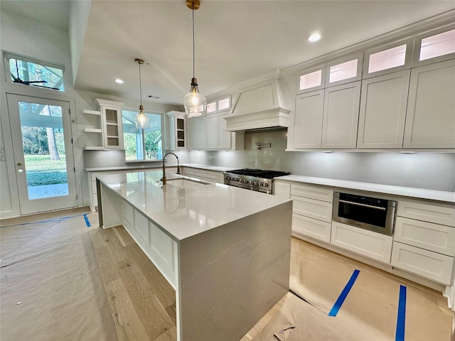 kitchen featuring premium range hood, stainless steel appliances, sink, white cabinetry, and hanging light fixtures