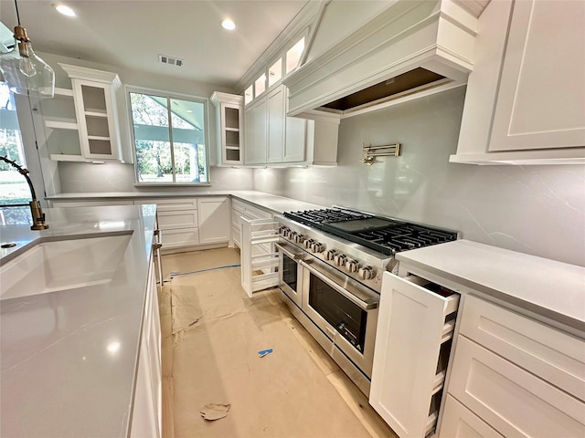 kitchen with white cabinets, custom exhaust hood, range with two ovens, and sink