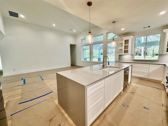 kitchen featuring sink, decorative light fixtures, dishwasher, white cabinetry, and an island with sink