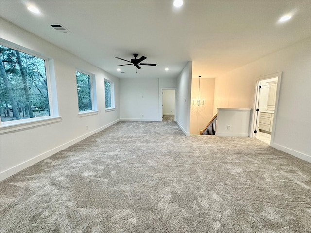 carpeted spare room with ceiling fan with notable chandelier