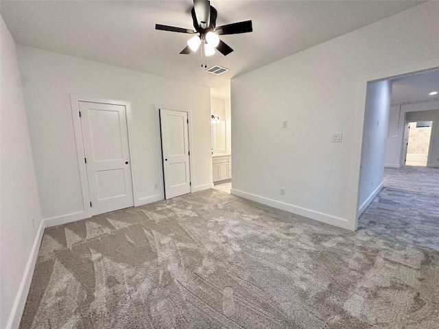 unfurnished bedroom featuring carpet floors, ensuite bath, and ceiling fan