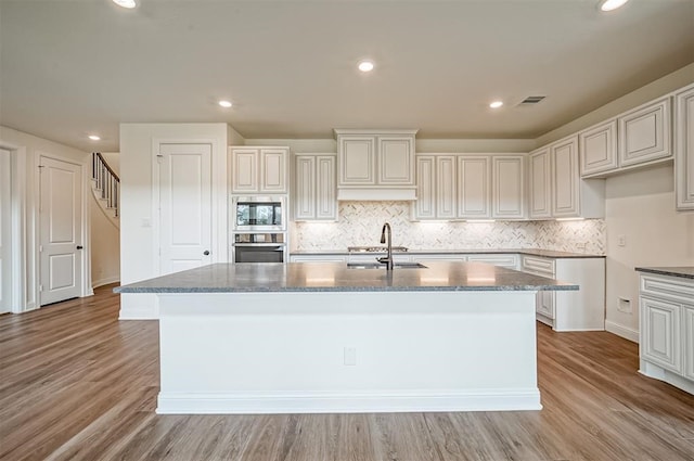 kitchen featuring a center island with sink, sink, light wood-type flooring, and appliances with stainless steel finishes