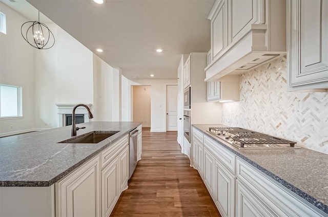 kitchen featuring stainless steel appliances, white cabinetry, sink, dark hardwood / wood-style floors, and a notable chandelier