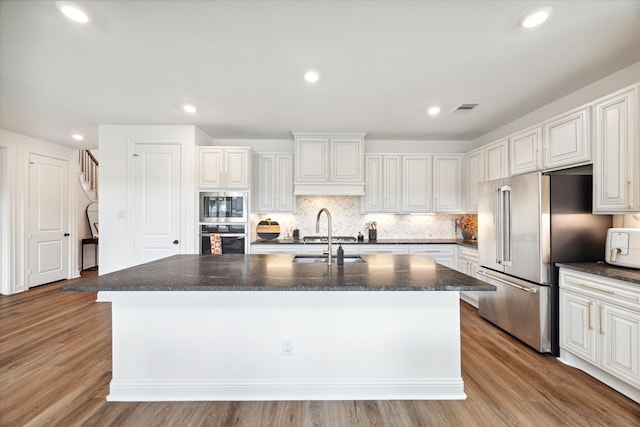 kitchen with white cabinetry, sink, appliances with stainless steel finishes, an island with sink, and light hardwood / wood-style flooring