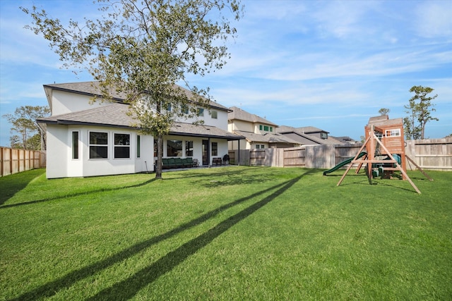 back of house featuring a playground and a lawn