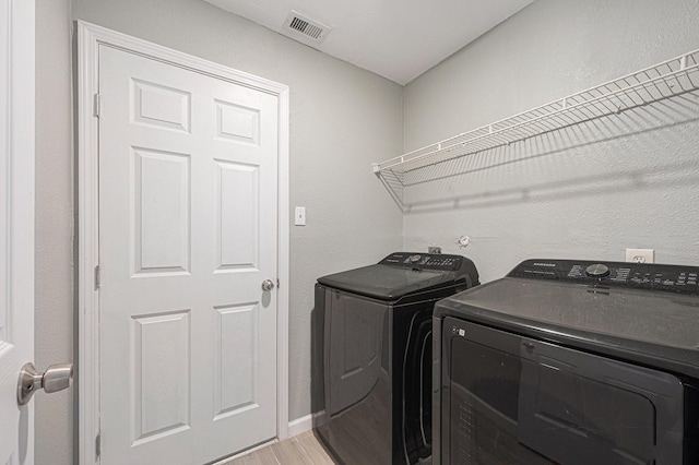 clothes washing area with light hardwood / wood-style floors and separate washer and dryer