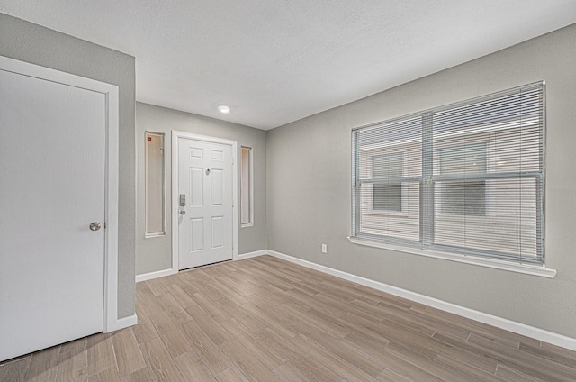 spare room with a textured ceiling and light wood-type flooring