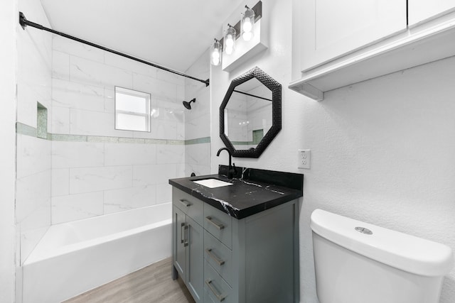 full bathroom with toilet, tiled shower / bath combo, vanity, and wood-type flooring