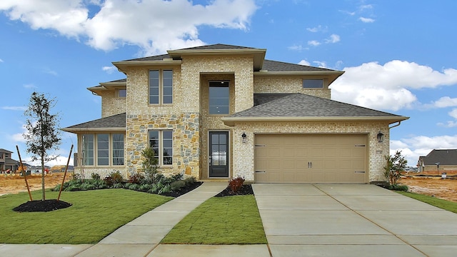 prairie-style house with a garage, concrete driveway, roof with shingles, a front yard, and brick siding